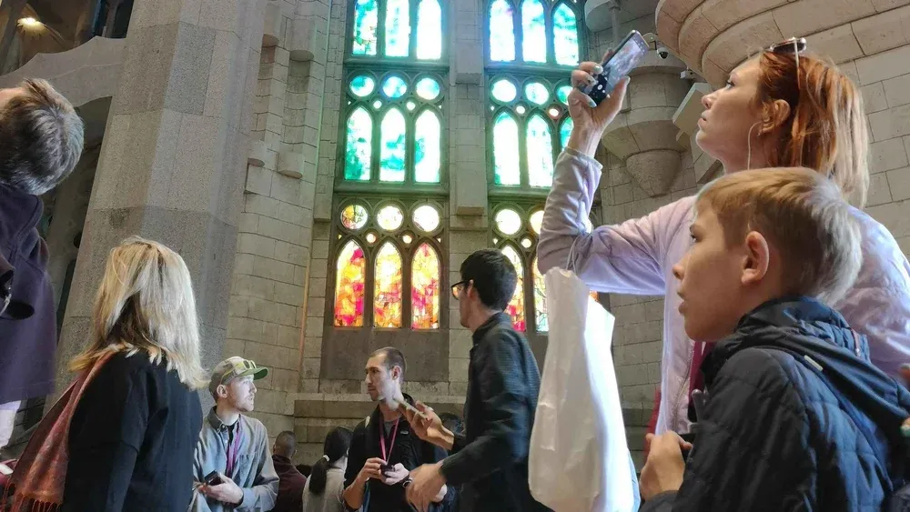 Official basilica guide explaining a stained glass window to two visitors on a private la sagrada familia tour
